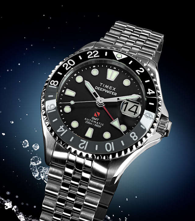 Timex Deepwater Meridian 200 Automatic GMT stainless steel watch with black dial and GMT bezel, shown with water splash accents on a dark blue background.