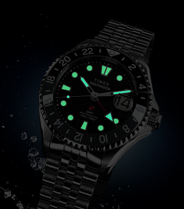 Timex Deepwater Meridian 200 Automatic GMT watch with luminous markers glowing in the dark, displayed against a black background with water splash effects.