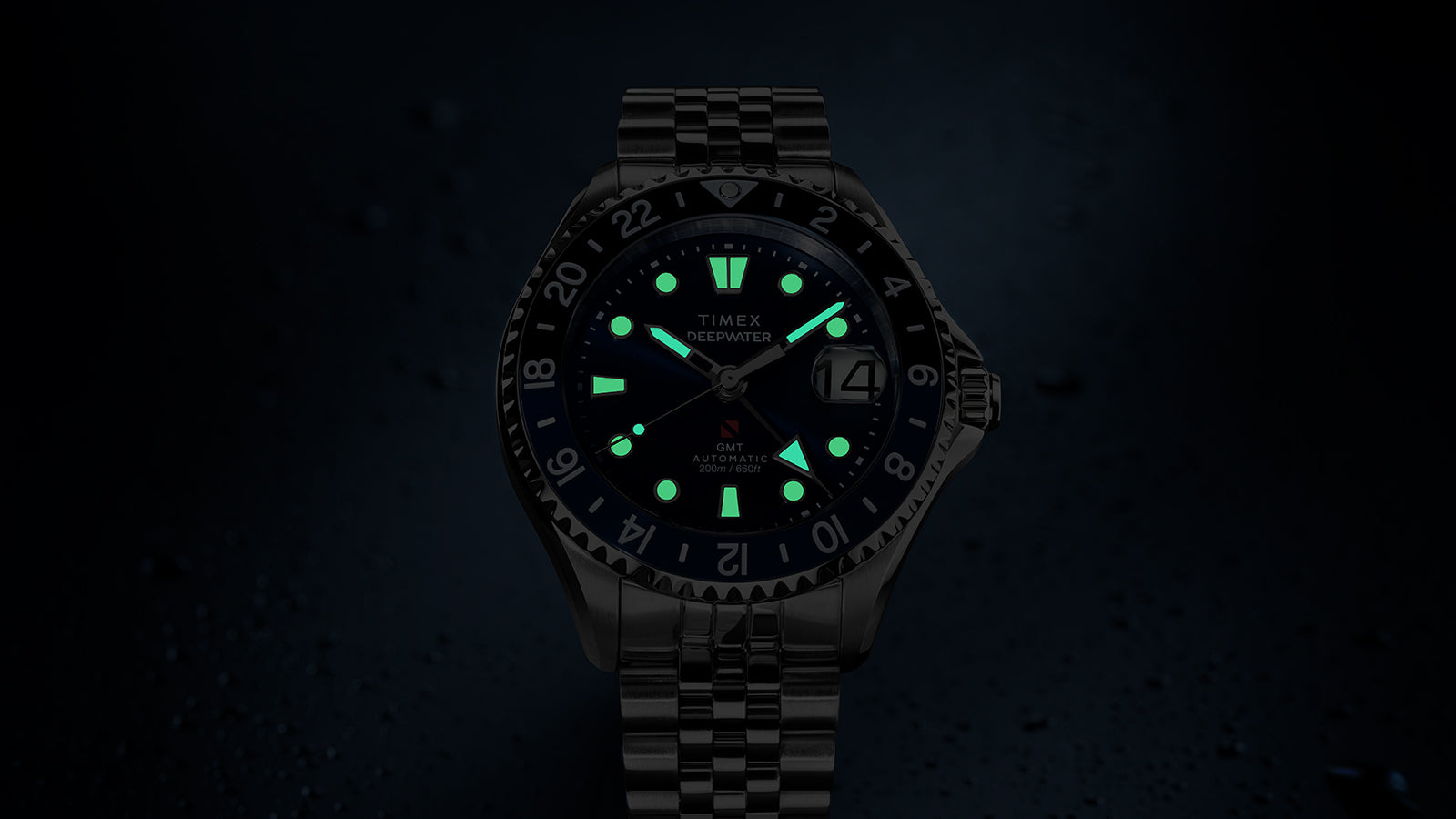 Timex Deepwater Meridian 200 Automatic GMT with luminous hands and hour markers glowing in low light to highlight nighttime readability.