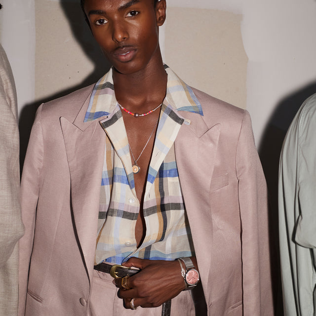 Person wearing the Todd Snyder x Timex Marlin® Mesh watch with a pink dial, paired with a pastel suit and plaid shirt.