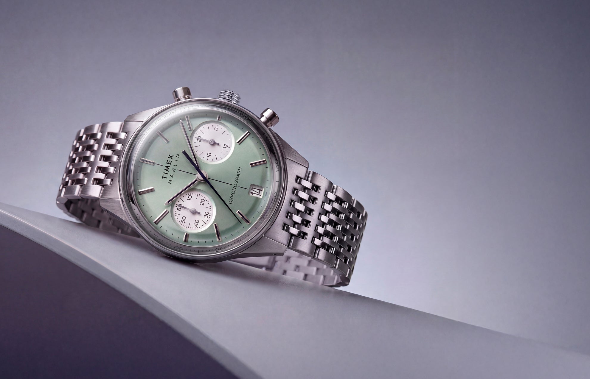 Timex Marlin® Jet Chronograph with a green dial and stainless-steel bracelet displayed on an angled surface.
