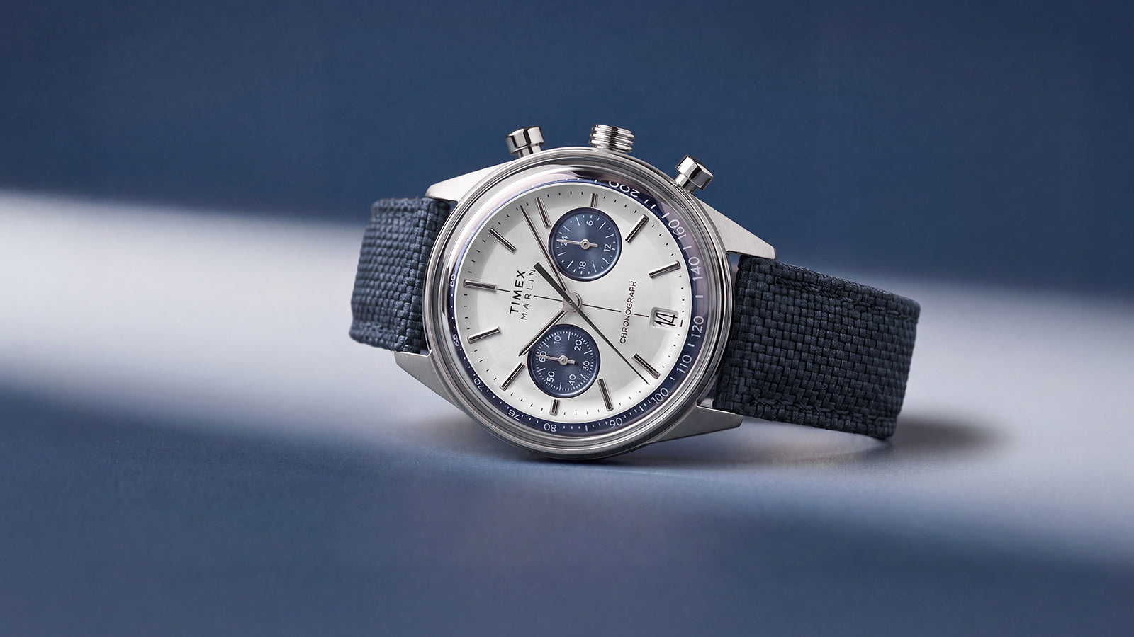 Timex Marlin® Jet Chronograph featuring a silver-tone dial, blue subdials, and textured blue fabric strap.