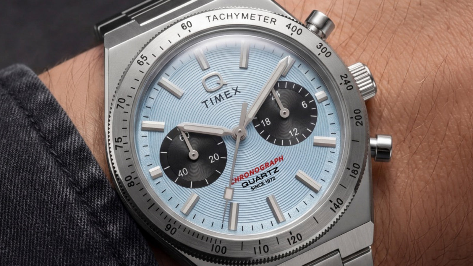 Close-up of the Q Timex Continental Chronograph on a wrist, highlighting its ice blue dial, black subdials, and stainless-steel tachymeter bezel.