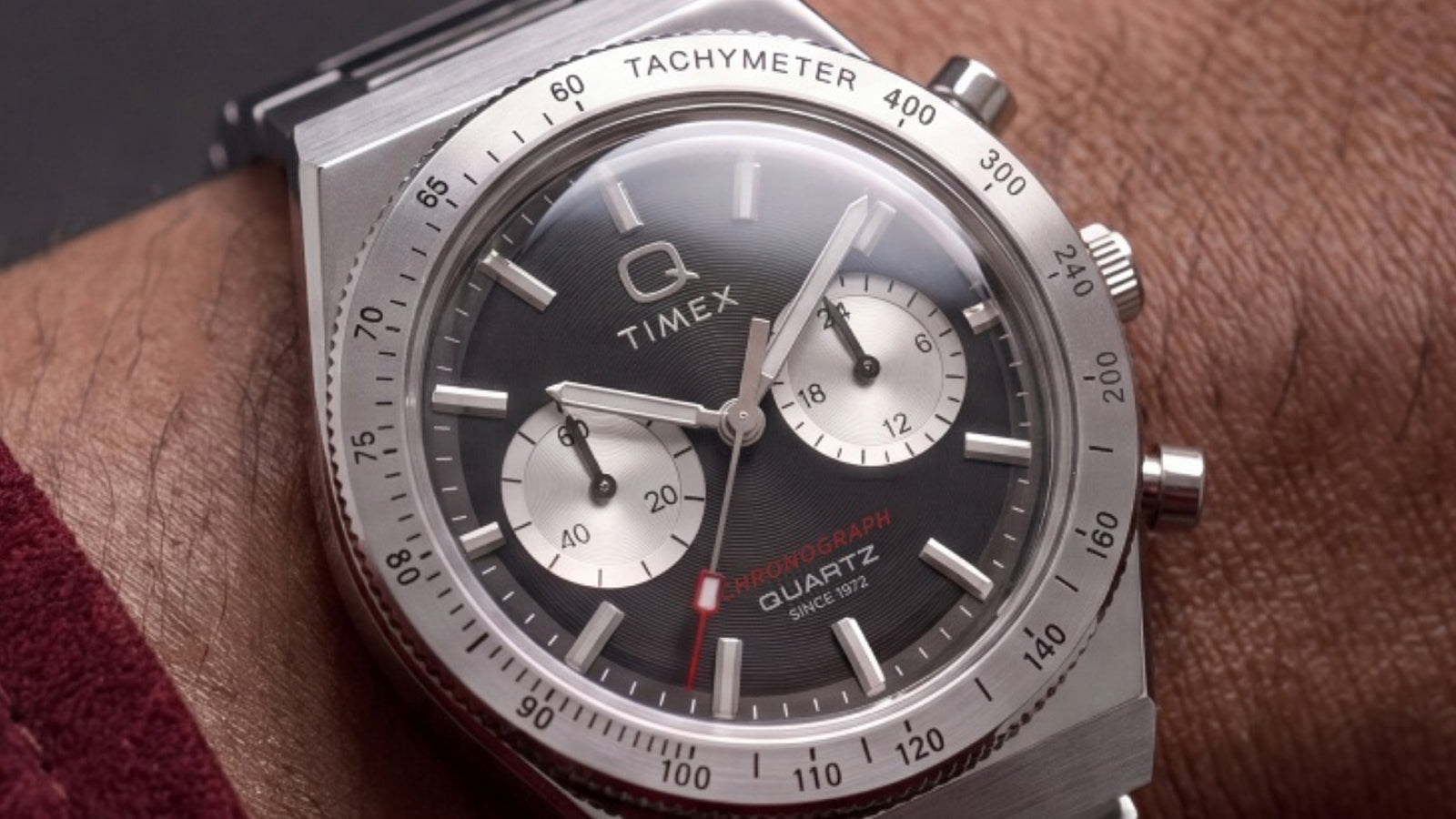 Close-up of the Q Timex Continental Chronograph on a wrist, highlighting its black dial, silver-tone subdials, and stainless-steel tachymeter bezel.