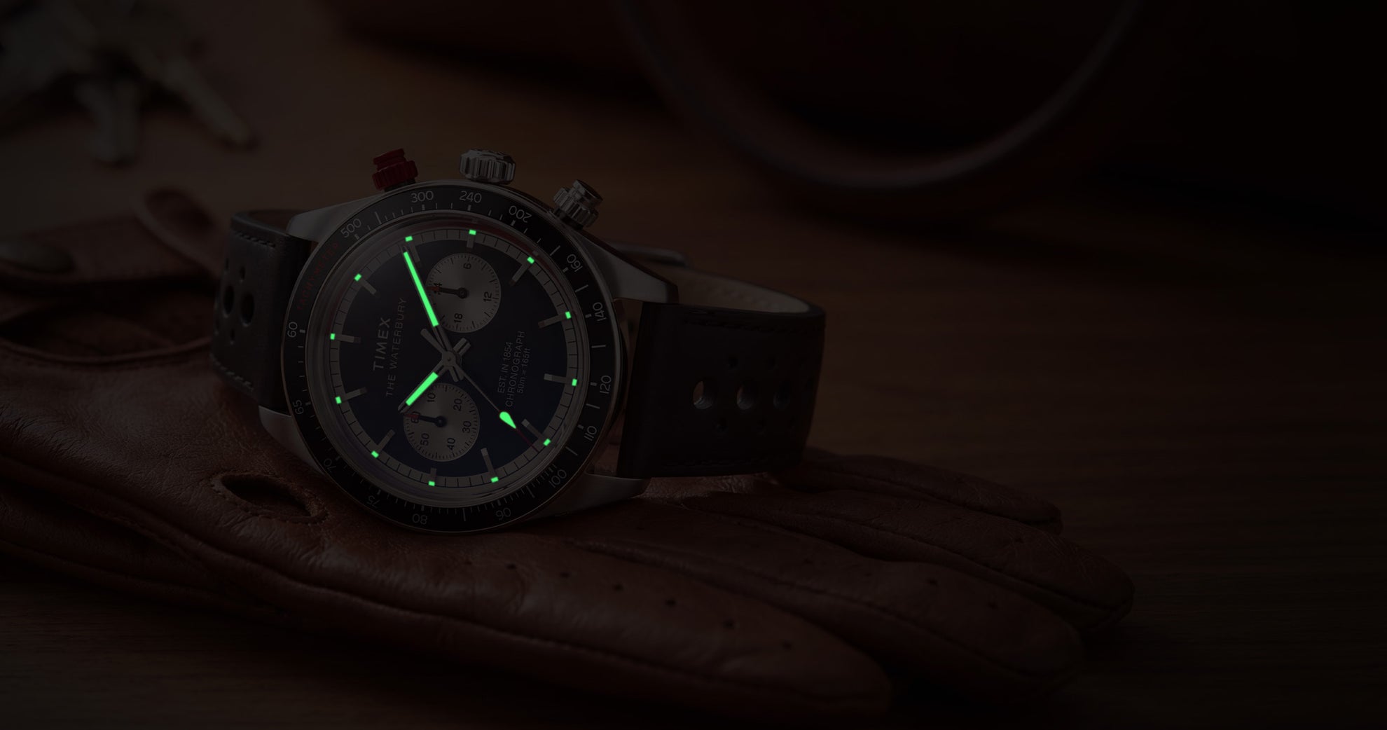 Timex Waterbury Heritage Chronograph with luminous hands and hour markers glowing in low light.