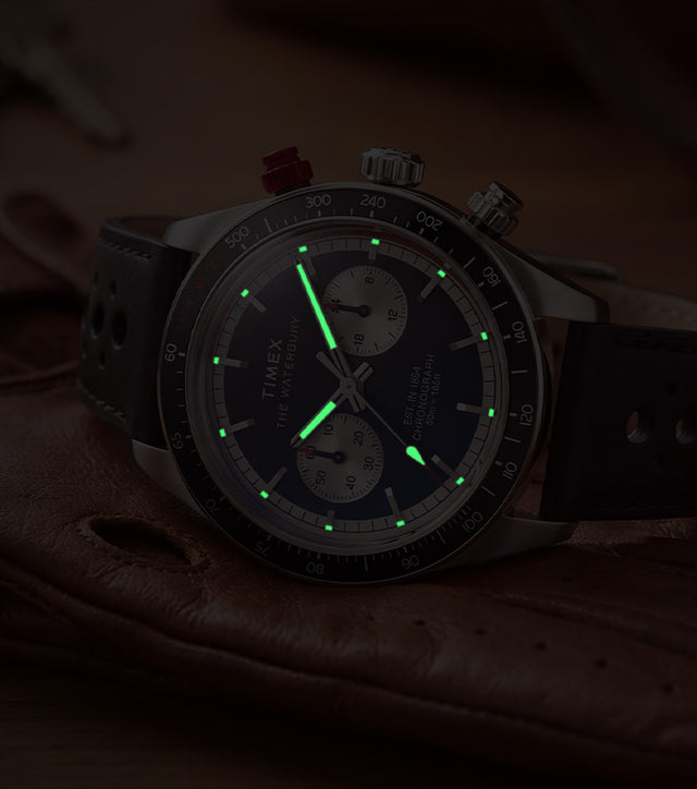 Timex Waterbury Heritage Chronograph with luminous hands and hour markers glowing in low light.