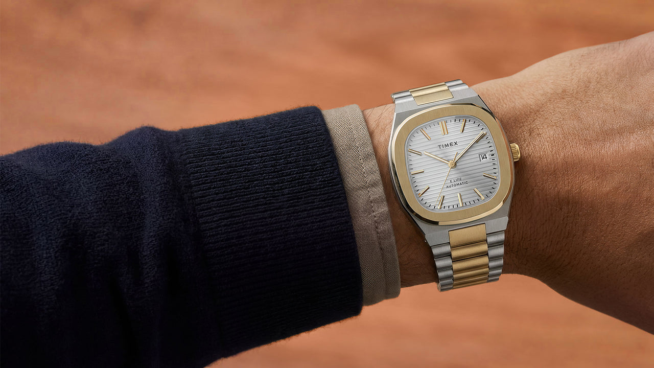 Close-up of the Timex® Automatic E Line 38mm two-tone stainless steel watch with a silver textured dial and date window worn on the wrist.