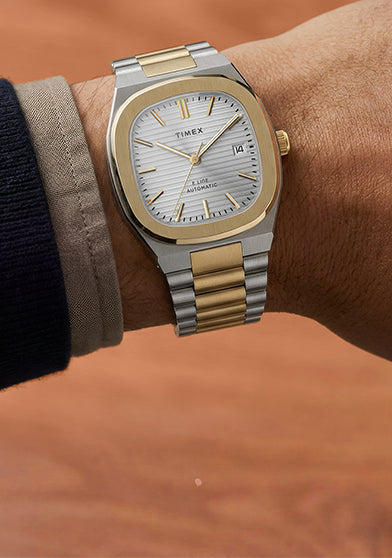 Close-up of the Timex® Automatic E Line 38mm two-tone stainless steel watch with a silver textured dial and date window worn on the wrist.