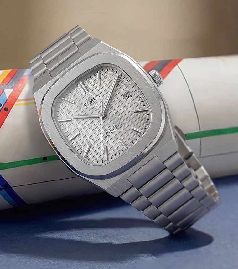 Reloj Timex® Automatic E Line de 38 mm con brazalete de acero inoxidable, esfera plateada con textura y ventana de fecha representada en un mapa enrollado del metro de Nueva York.