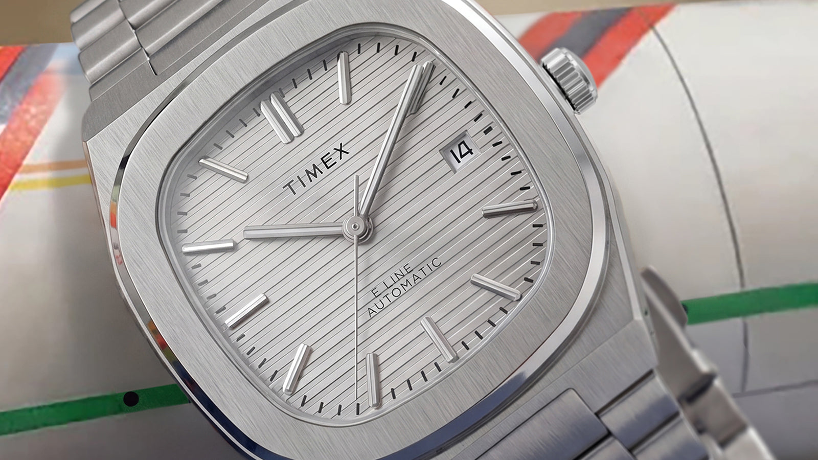 Primer plano del Timex® Automatic E Line de 38 mm, con esfera plateada texturizada, ventana de fecha, caja de acero inoxidable cepillado y brazalete integrado de acero inoxidable.