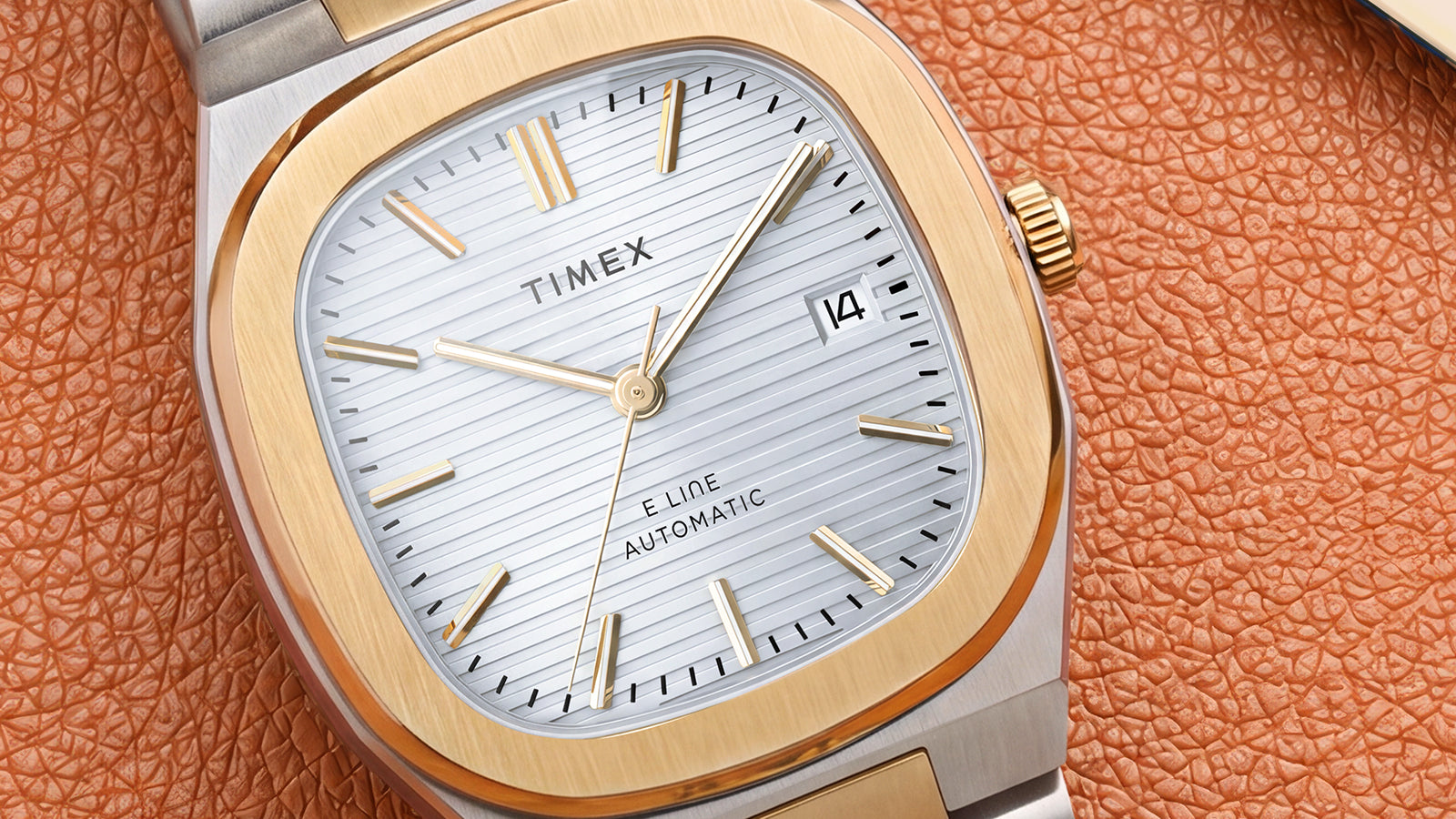 Close-up of the Timex® Automatic E Line watch featuring a silver textured dial, gold-tone markers and date window.