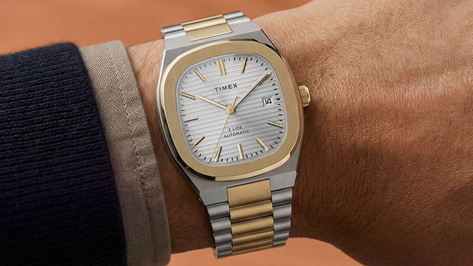 Close-up of the Timex Automatic E Line 38mm on the wrist, highlighting its gold-tone bezel, silver-tone dial, and date window.