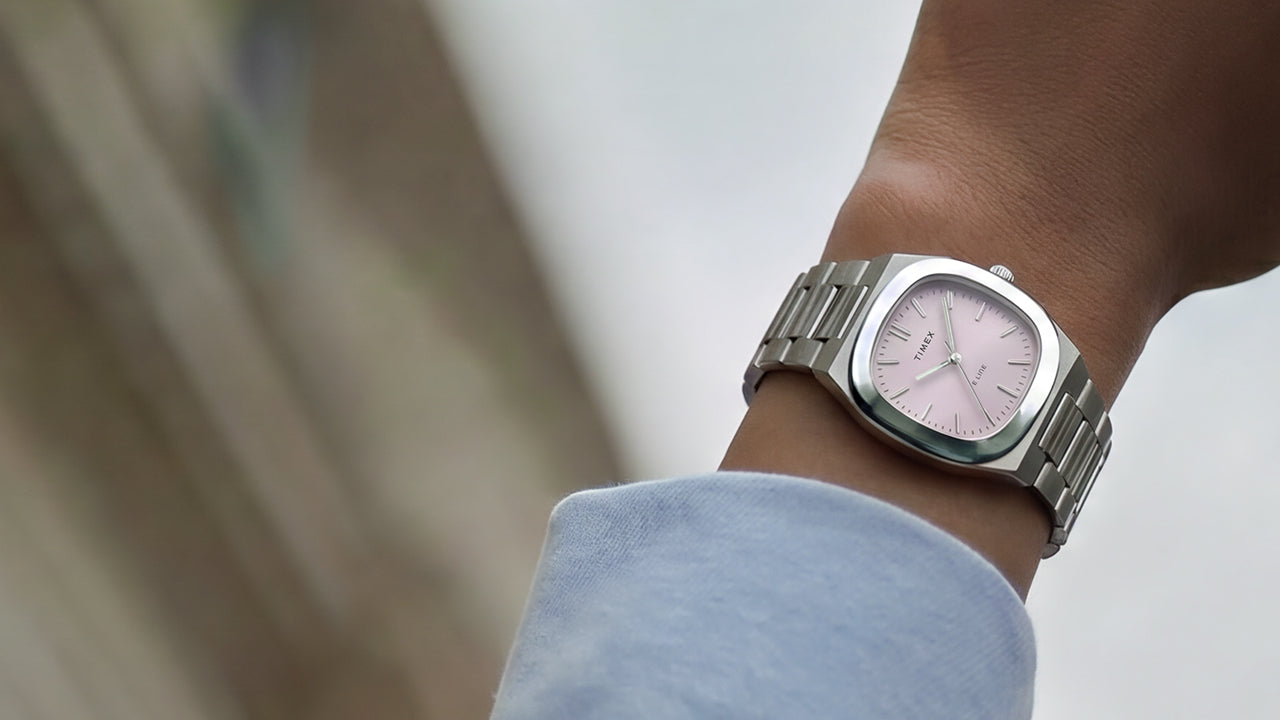 Primer plano del reloj Timex® Quartz E Line de 30 mm, de acero inoxidable y con esfera rosa con acabado rayos de sol, puesto en la muñeca.