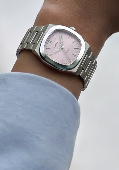 Primer plano del reloj Timex® Quartz E Line de 30 mm, de acero inoxidable y con esfera rosa con acabado rayos de sol, puesto en la muñeca.