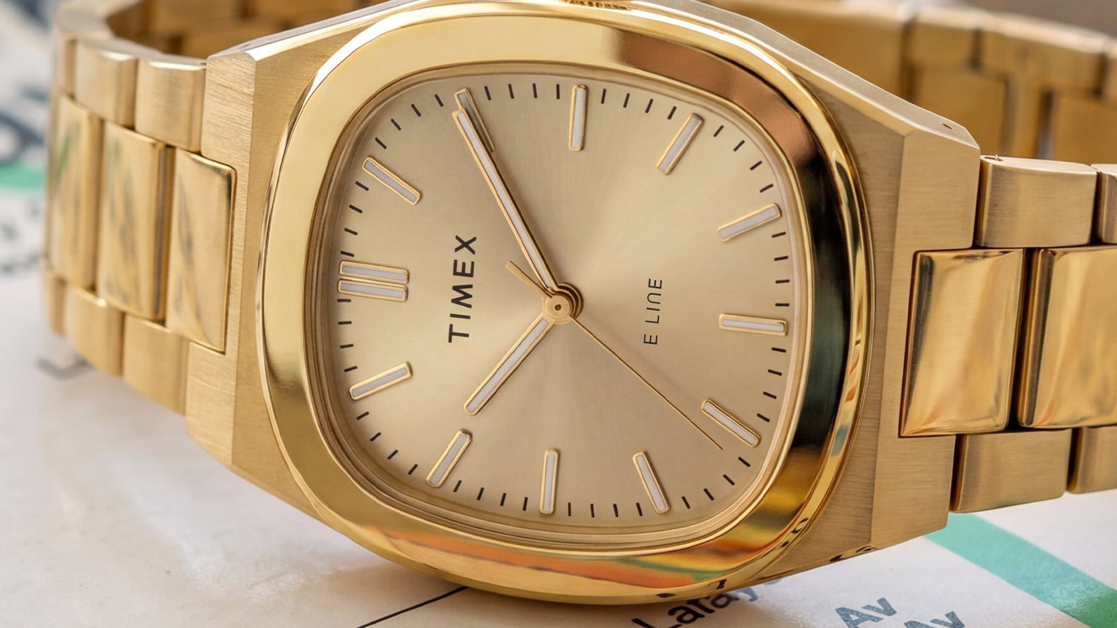 Primer plano del Timex® Quartz E Line de 30 mm, con una esfera color champán con acabado rayos de sol, caja pulida en tono dorado y brazalete de acero inoxidable en tono dorado.
