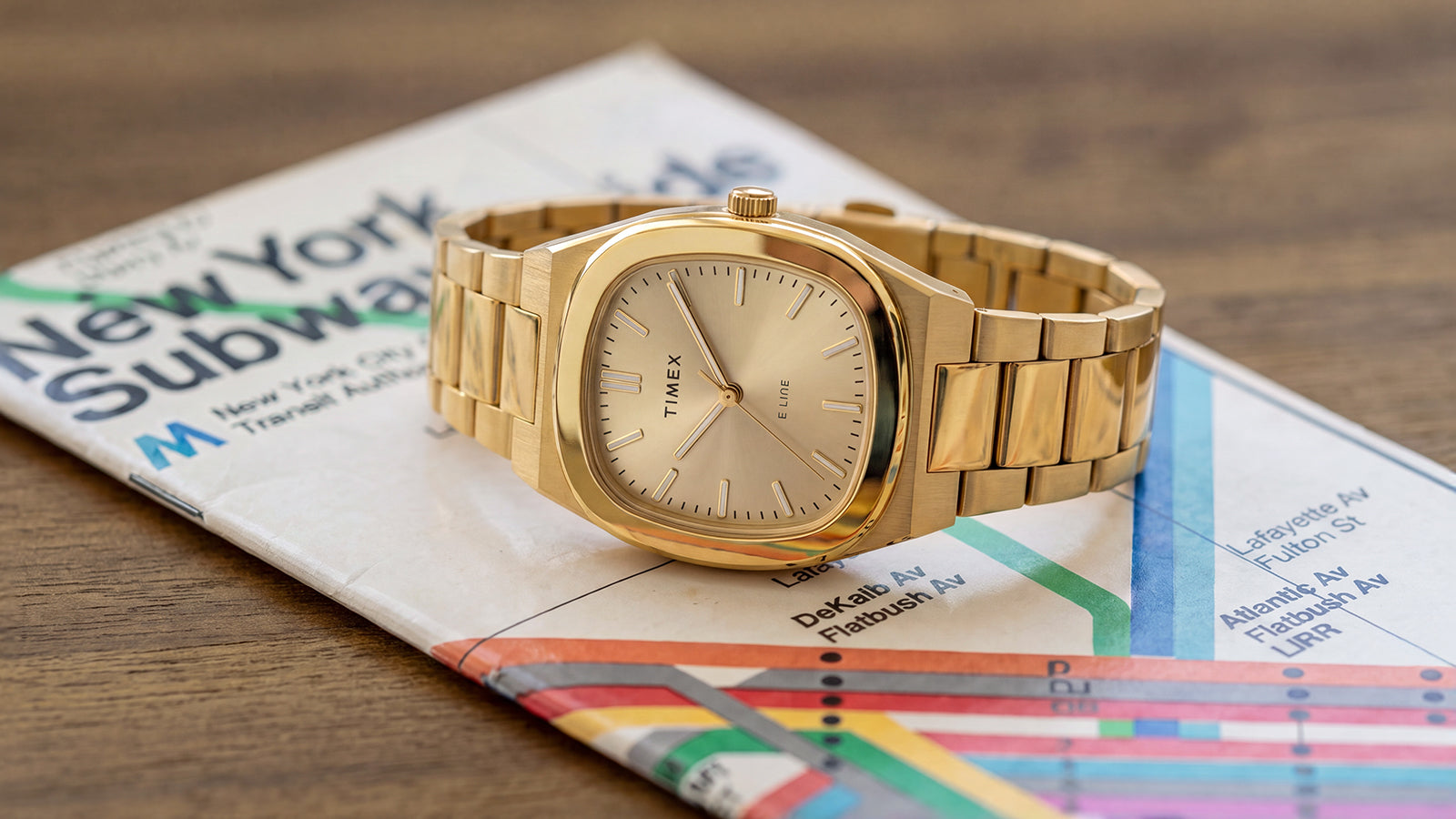 Primer plano del reloj Timex® Quartz E Line de 30 mm, de acero inoxidable en tono dorado, expuesto sobre un mapa del metro de Nueva York.