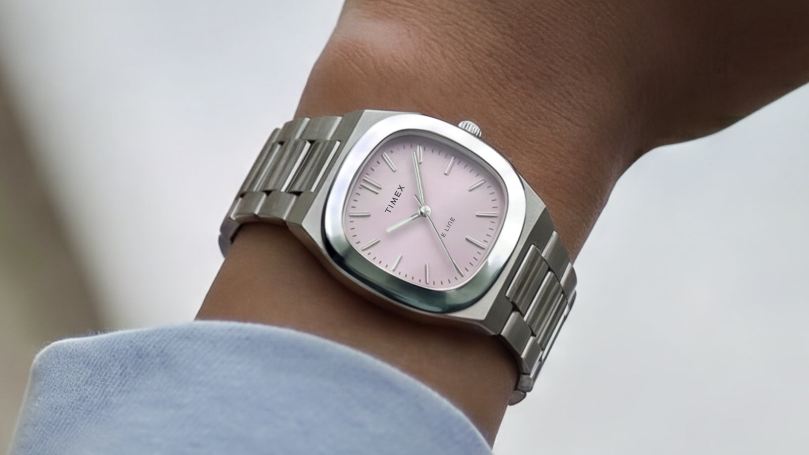 Reloj Timex® Quartz E Line de 30 mm, de acero inoxidable, con esfera rosa con acabado rayos de sol, puesto en la muñeca.