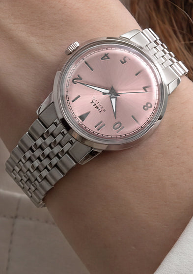 Close-up of the Timex Marlin Quartz with a pink sunray dial and stainless steel bracelet worn on the wrist.