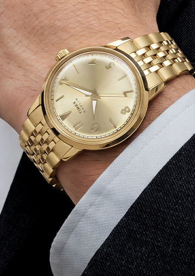 Timex Marlin Quartz with a champagne sunray dial and gold-tone stainless steel bracelet worn on the wrist.