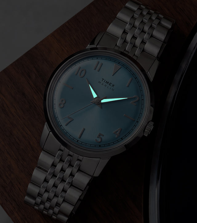 Timex Marlin Quartz watch with luminous hands glowing in low light beside a vinyl record.
