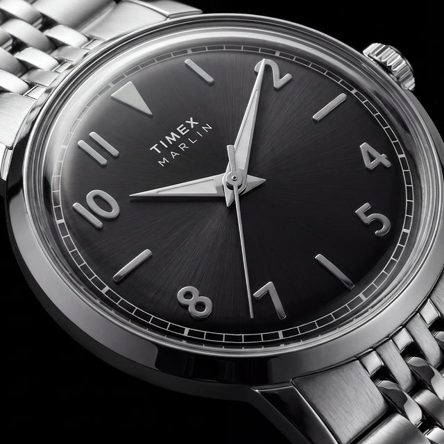 Macro view of the Timex Marlin Quartz black sunray dial with applied silver-tone Arabic numerals, luminous hands, and polished stainless steel case.