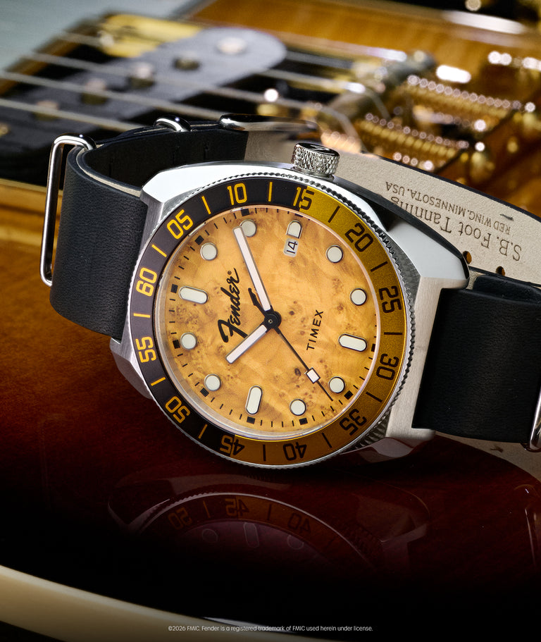 TW6A14600 Fender x Timex Automatic watch with a wood-grain dial, black strap, silver-tone case, and rotating bezel displayed on a Fender guitar.