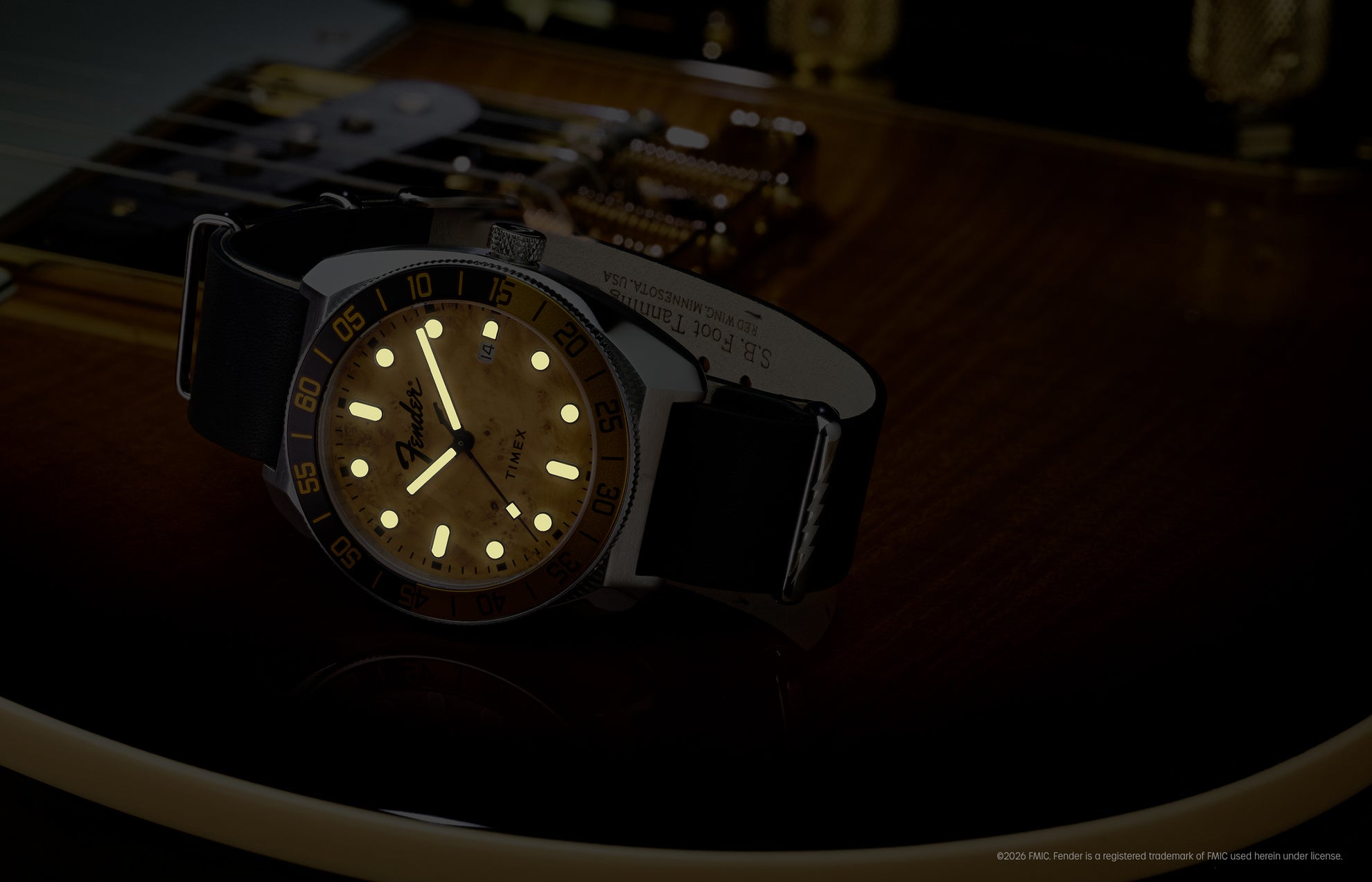 Fender x Timex Automatic with illuminated hands and hour markers displayed on a Fender guitar in low light.