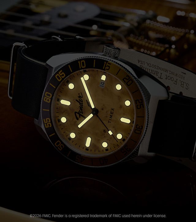 Fender x Timex Automatic with illuminated hands and hour markers displayed on a Fender guitar in low light.