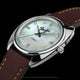 Angled close-up of the Fender x Timex watch highlighting its mother-of-pearl dial, brown leather strap, and tone-inspired crown.