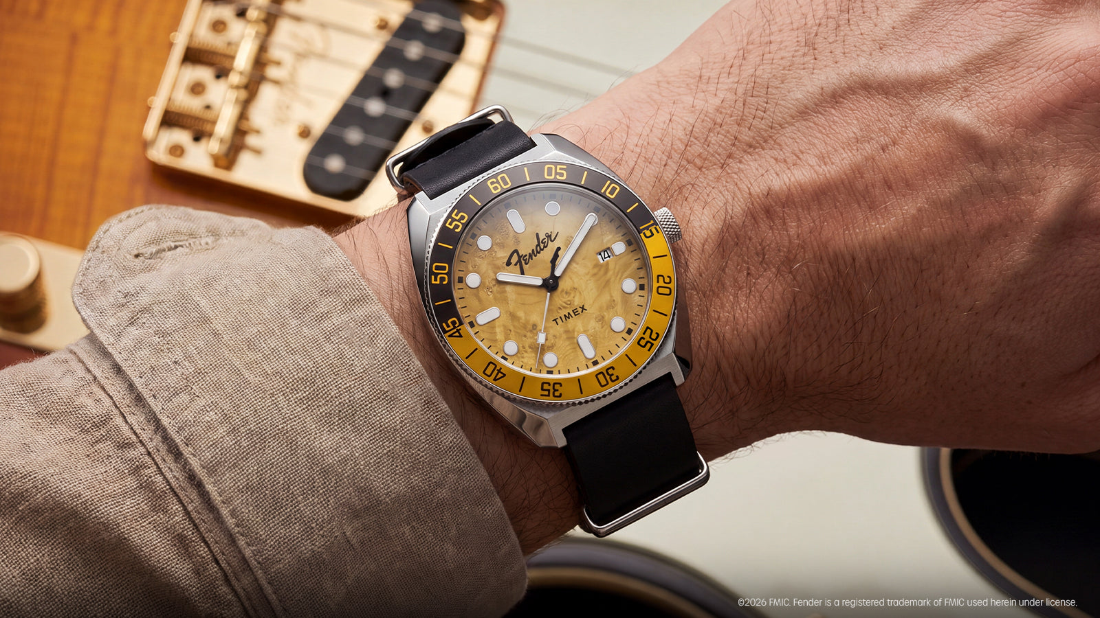 Close-up of the Fender x Timex Automatic worn on the wrist, highlighting its amber wood-grain dial and black leather strap.