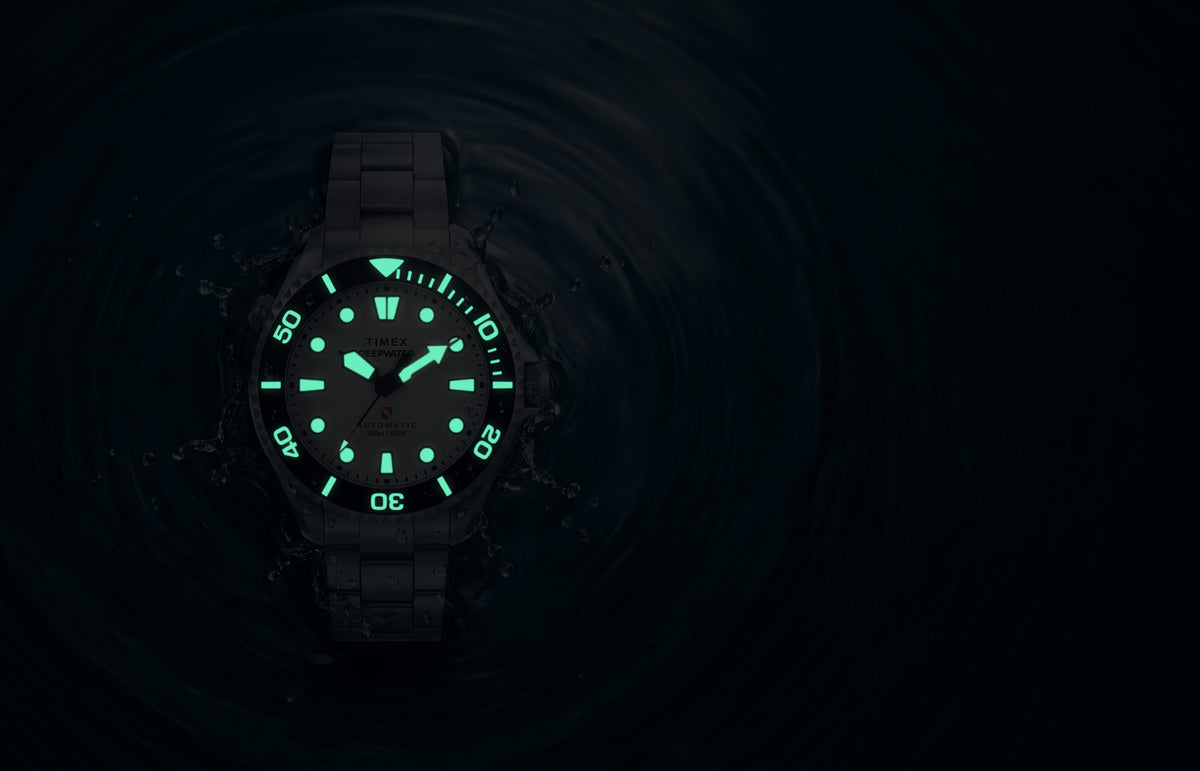 Deepwater Meridian 200 HEV Automatic surrounded by water in low light with illuminated dial and bezel markers.