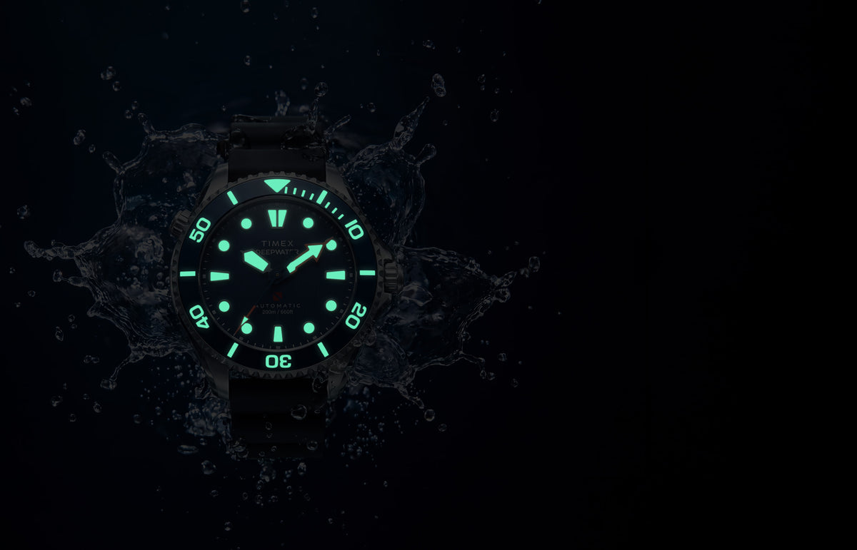 Deepwater Meridian 200 HEV Automatic surrounded by water in low light with glowing dial and bezel markers.