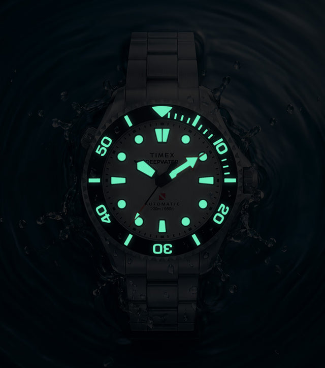Deepwater Meridian 200 HEV Automatic surrounded by water in low light with illuminated dial and bezel markers.