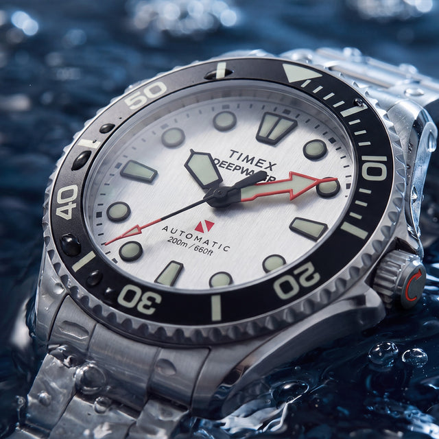 Close-up of the Deepwater Meridian 200 HEV Automatic’s silver-tone dial, luminous markers, red arrow hands, and black dive bezel.