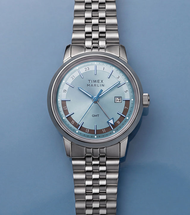Marlin® Quartz GMT with an icy blue dial and stainless-steel bracelet displayed on a blue surface.