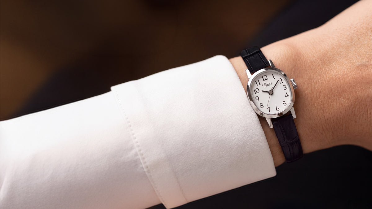 Cavatina® Mini watch with a white dial and black leather strap worn on a wrist.