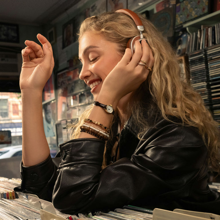 Una mujer que lleva el reloj Cavatina® Mini mientras escucha música con los auriculares y echa un vistazo a los discos.