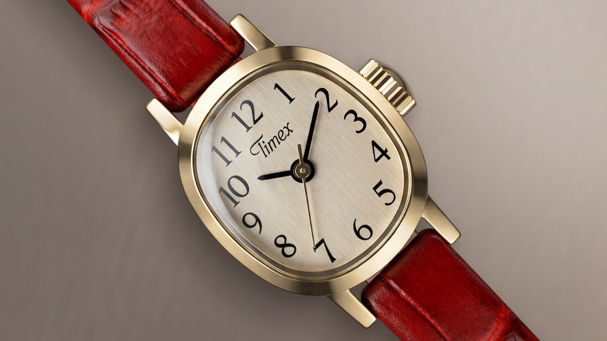 Close-up of the Cavatina® Mini featuring a gold-tone case, champagne dial, black Arabic numerals, and red leather strap.