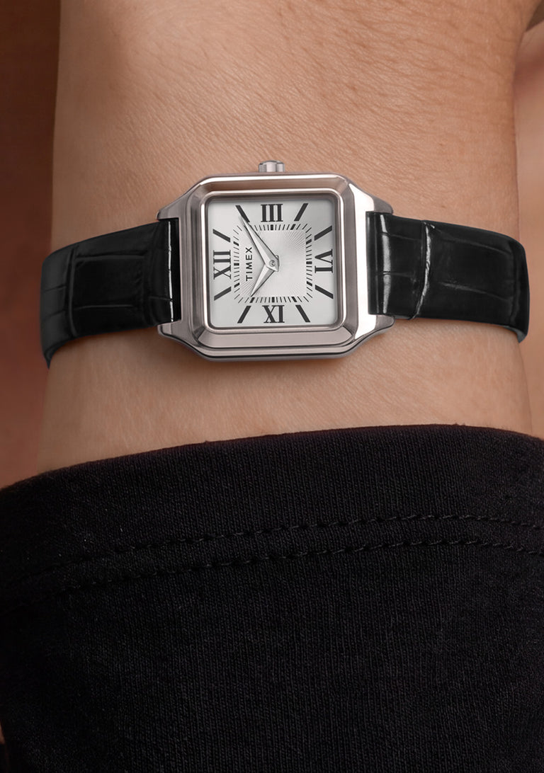 Timex Addison watch with a silver-tone rectangular case and black leather strap worn on the wrist.