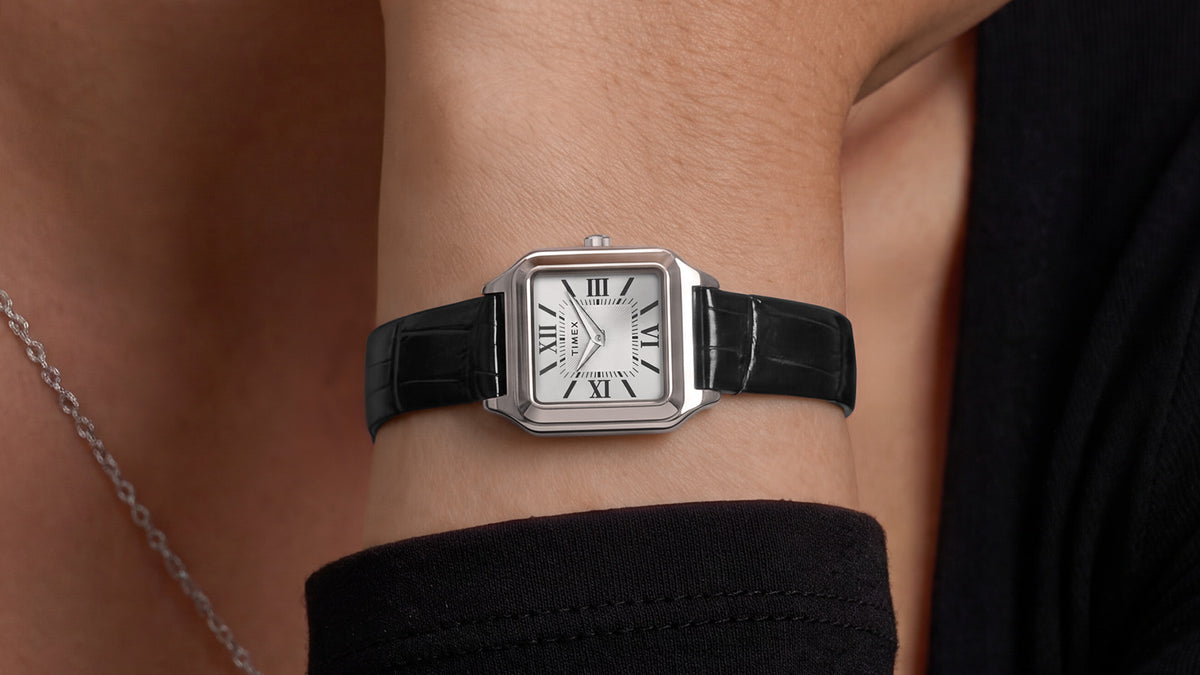Close-up of the Timex Addison watch styled on the wrist with a black outfit and silver necklace.