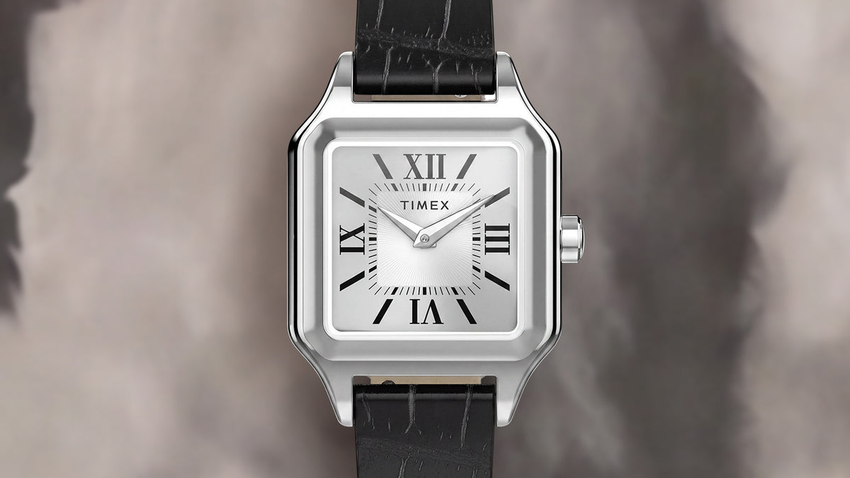 Front view of the Timex Addison watch featuring a silver-tone rectangular case, white dial, black Roman numerals, and black leather strap.