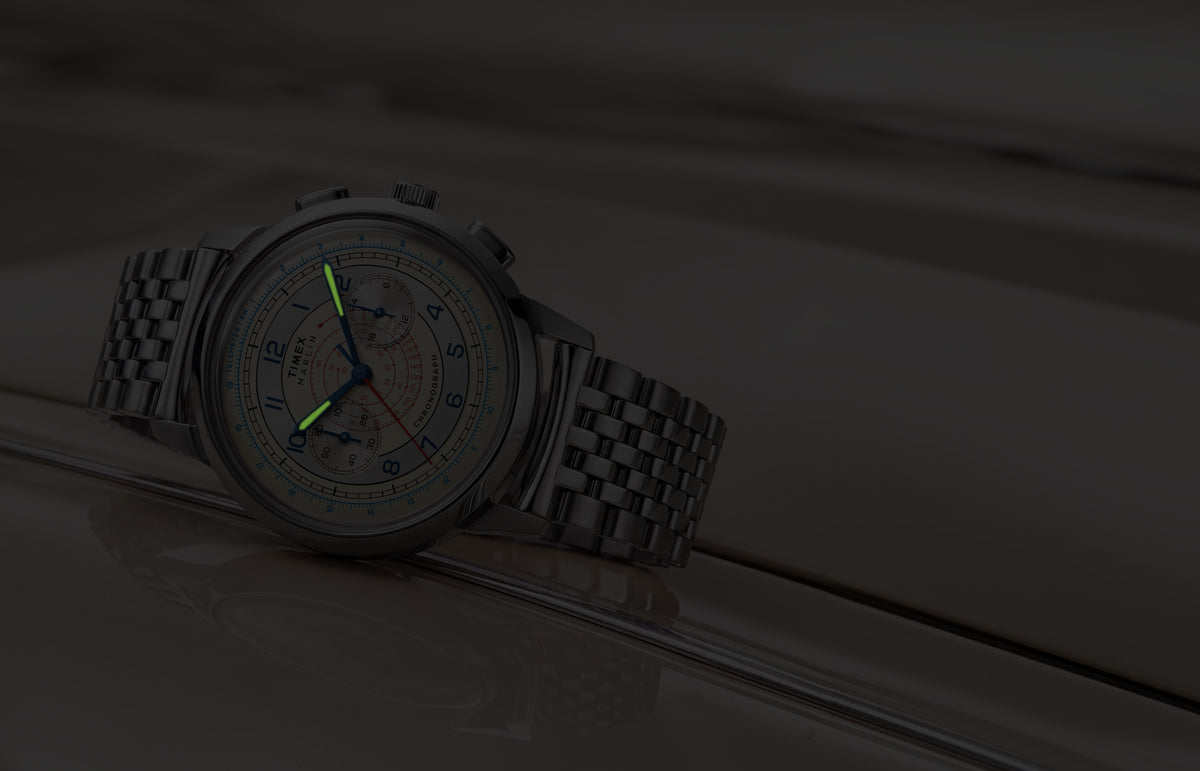 Marlin® Neo Classic Chronograph resting on a cream-colored car in low light with green luminous hands.