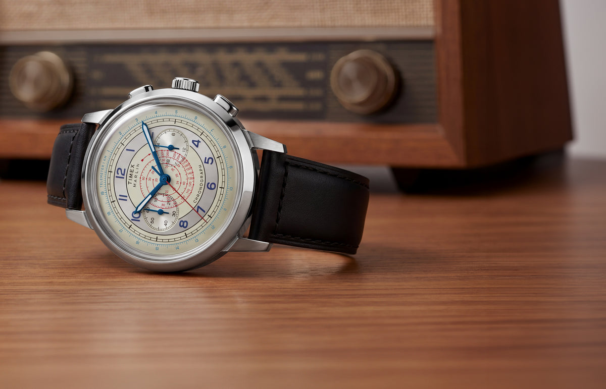 Marlin® Neo Classic Chronograph with a cream multiscale dial and black leather strap displayed on a wooden surface beside a vintage radio.