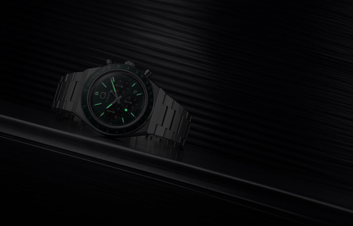 Q Timex Chronograph in low light, highlighting the glowing hands and hour markers.