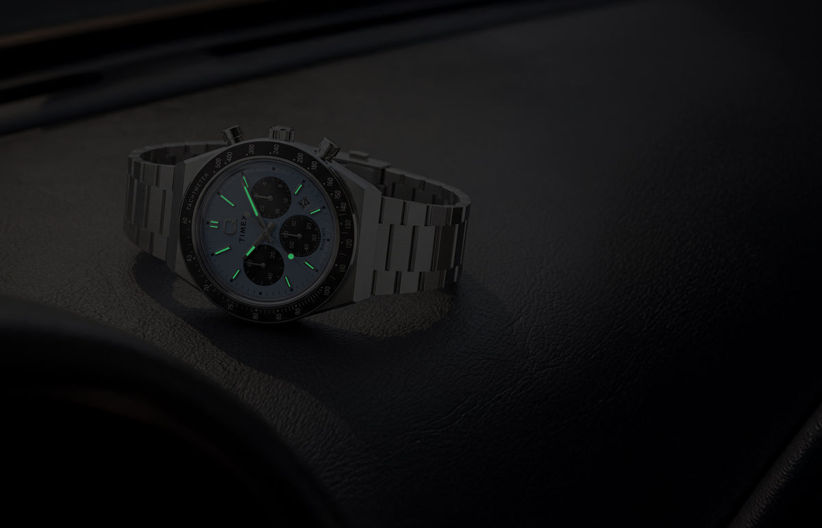 Q Timex Chronograph in low light, highlighting its glowing hands and hour markers.