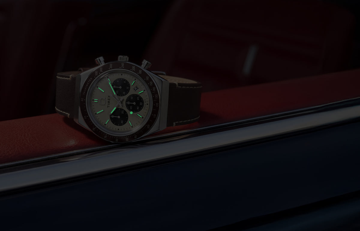 Q Timex Chronograph in low light, highlighting its glowing hands and hour markers.