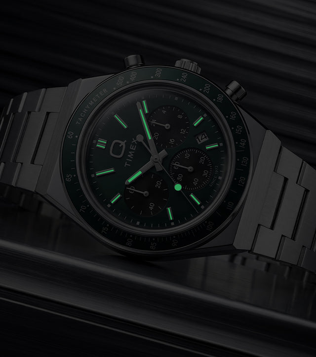 Q Timex Chronograph in low light, highlighting the glowing hands and hour markers.