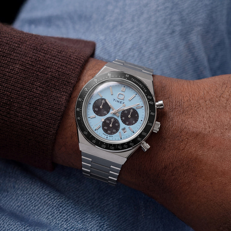 Ice-blue Q Timex Chronograph with black subdials and a stainless-steel bracelet worn on the wrist.