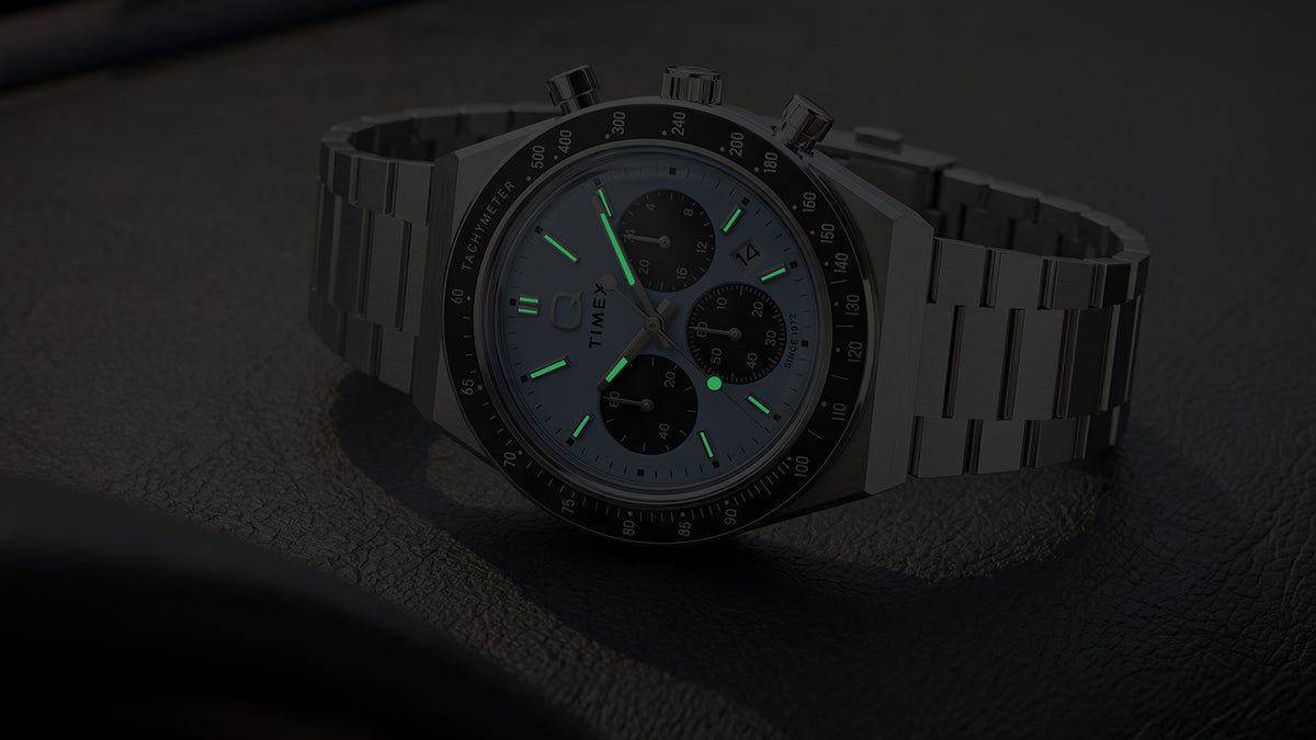 Q Timex Chronograph in darkness with illuminated hands and hour markers.