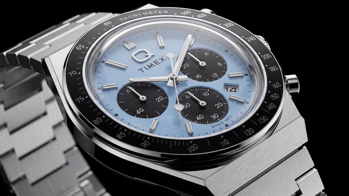Angled close-up of the ice-blue Q Timex Chronograph with black subdials and a stainless-steel bracelet.